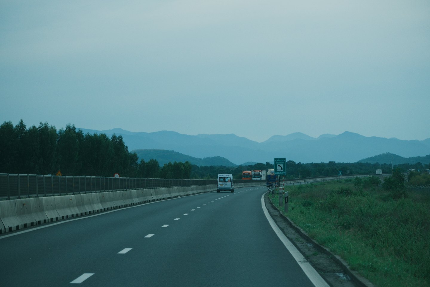 Ciężarówki i van jadą autostradą w stronę gór.