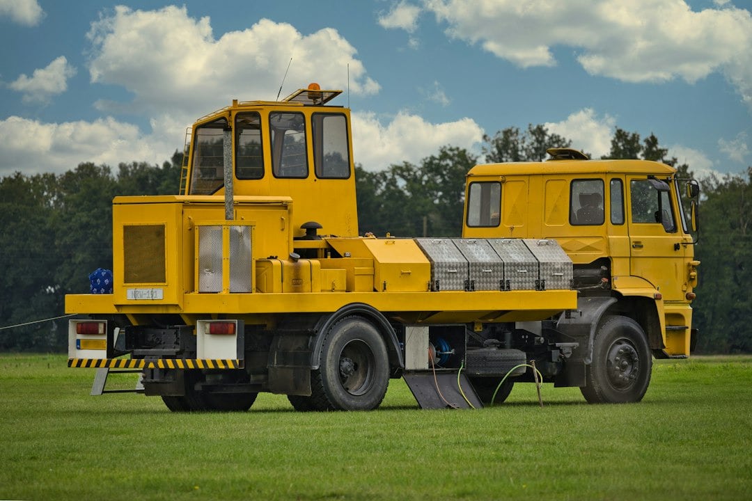 A yellow industrial vehicle parked on a grassy field.